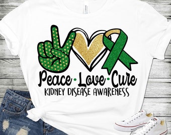 May include: White t-shirt with a green peace sign, gold heart, and green ribbon. The text "Peace - Love - Cure Kidney Disease Awareness" is printed below the symbols.