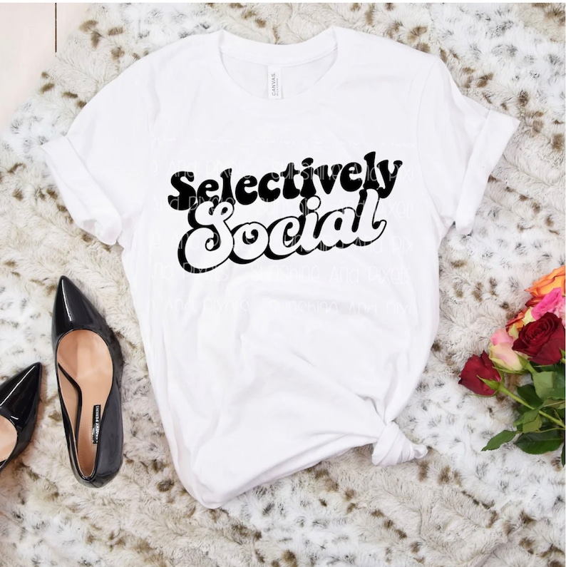 May include: White t-shirt with black text that reads "Selectively Social" in a retro font style.