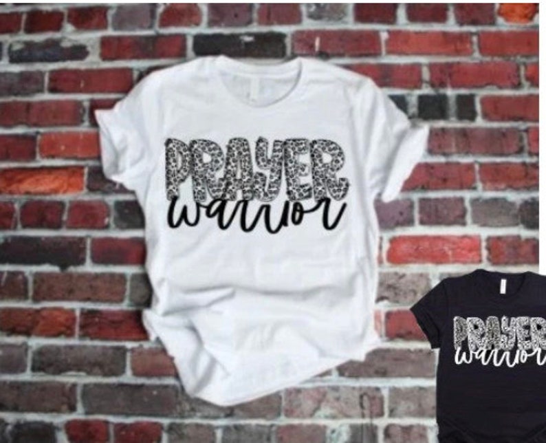 May include: White t-shirt with the words "Prayer Warrior" in black lettering. The word "Prayer" is made up of a leopard print pattern.
