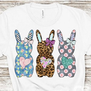 Könnte beinhalten: Drei Osterhasen-Figuren mit verschiedenen Mustern. Der Hase links ist blau mit einem Blumenmuster und einem rosa Herzen. Der mittlere Hase ist braun mit einem Leopardenmuster und einem Blumenherz. Der Hase rechts ist grau mit einem Blumenmuster und einem türkisfarbenen Herzen.