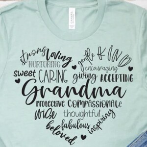 May include: A light blue t-shirt with a black heart design featuring the word "Grandma" surrounded by words describing her personality, such as "strong", "loving", "gentle", "kind", "caring", "giving", "accepting", "protective", "compassionate", "wise", "thoughtful", "fabulous", "inspiring", and "beloved".