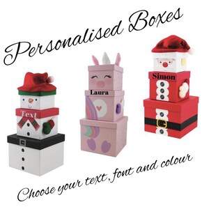 May include: Three stackable gift boxes with personalised names. The boxes are decorated with a snowman, a unicorn, and Santa Claus. The text "Choose your text, font and colour" is written below the boxes.