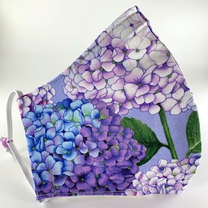 May include: Purple and blue hydrangea flower print face mask with white elastic straps.