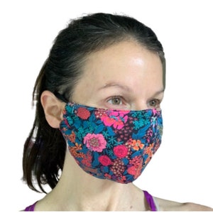 May include: A person wearing a black face mask with a floral pattern featuring pink, red, and blue flowers on a dark blue background.