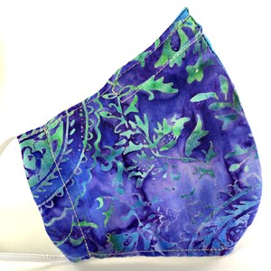 May include: A blue and green patterned face mask with white stitching. The mask is made of fabric and has a floral design.