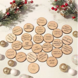 Puede incluir: C&iacute;rculos de madera de actividades navide&ntilde;as con varias actividades tem&aacute;ticas navide&ntilde;as escritas en ellos, como "Hacer una donaci&oacute;n", "Ir a ver las luces de Navidad", "Escuchar m&uacute;sica navide&ntilde;a", "Noche de pizza", "Hacer copos de nieve de papel", "Leer un libro de Navidad", "M&aacute;s decoraciones de &aacute;rboles", "Actividad divertida", "Ver una pel&iacute;cula navide&ntilde;a", "D&iacute;a de pijama", "Hacer s'mores", "Comer bastones de caramelo", "Escribir una carta a Santa", "Sin tareas", "Hornear galletas para Santa", "Noche de juegos", "Hacer una lista de gratitud", "Envolver regalos", "Hacer una casa de pan de jengibre", "Hacer una corona", "Vestir de rojo", "Hacer comida para renos", "Chocolate caliente y malvaviscos", "Hacer una tarjeta de Navidad".