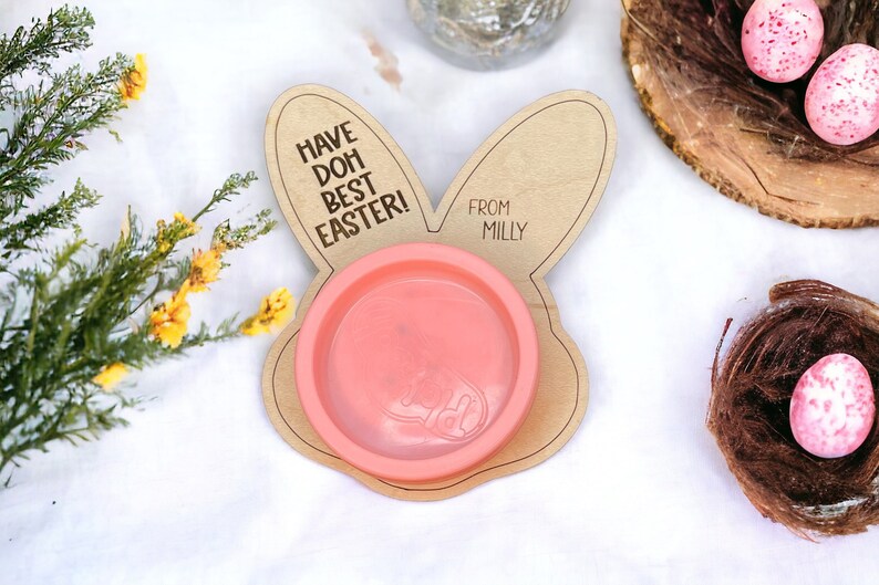 May include: A wooden bunny-shaped plate with a pink bowl in the center. The plate has the text "Have Doh Best Easter!" and "From Milly" engraved on it.