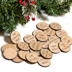 Puede incluir: Un conjunto de 20 fichas de actividades navide&ntilde;as de madera con varias actividades tem&aacute;ticas navide&ntilde;as escritas en ellas, como "Hornear galletas para Santa", "Hacer Smores", "Noche de juegos" y "D&iacute;a de pijama".