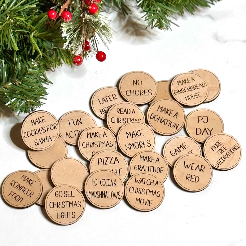 Puede incluir: Un conjunto de 16 fichas de actividades navide&ntilde;as de madera con varias actividades tem&aacute;ticas navide&ntilde;as escritas en ellas, como "Hornear galletas para Santa", "Hacer un adorno navide&ntilde;o", "Ver una pel&iacute;cula navide&ntilde;a" y "Ir a ver las luces navide&ntilde;as".