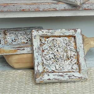 Può includere: Due scatole di legno decorative con una finitura di vernice bianca invecchiata e intagli floreali intricati. Le scatole hanno una base in legno marrone chiaro e sono accentate con vernice dorata.