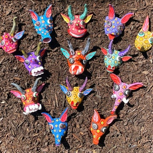 May include: A collection of colorful, hand-painted animal masks. Each mask features unique designs with vibrant colors like blue, red, yellow, and purple. The masks have horns, ears, and expressive faces, showcasing intricate details and patterns.
