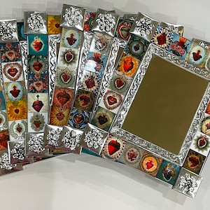 Könnte beinhalten: Satz von fünf silberfarbenen gerahmten Spiegeln mit bunten Mosaikfliesen, die heilige Herzen darstellen. Jeder Rahmen hat an den Ecken ein dekoratives Blumenmuster.