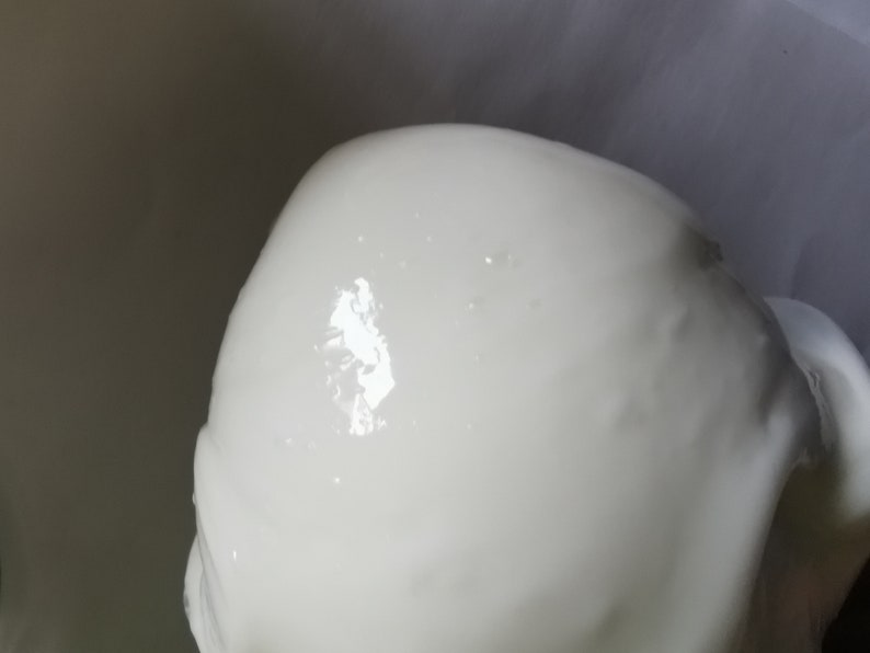 May include: A close-up of a white, smooth, and shiny surface. The surface is slightly textured and has a few small, dark spots.
