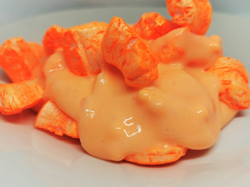 Puede incluir: Piezas de cereal inflado de color naranja cubiertas con una salsa cremosa naranja en un plato blanco.