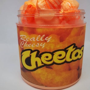 Puede incluir: Un tarro de pl&aacute;stico transparente lleno de slime naranja y blanco con forma de Cheetos. El tarro tiene una etiqueta que dice "Really Cheesy Cheetos".