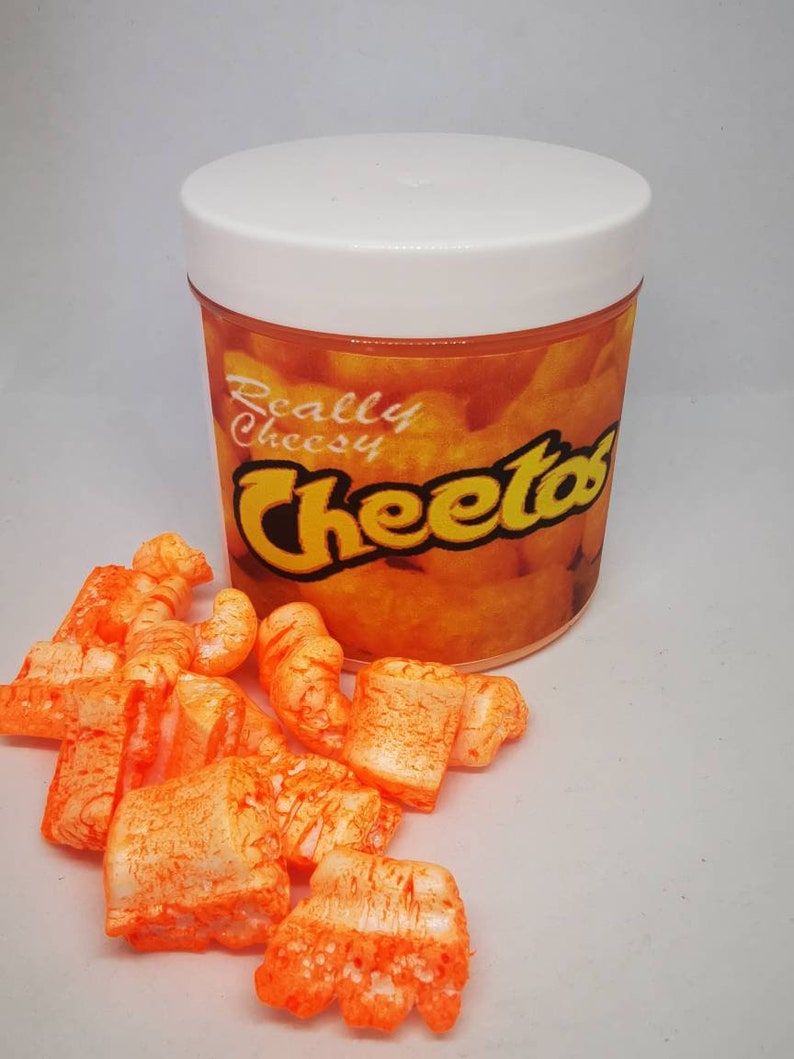 Puede incluir: Un recipiente de pl&aacute;stico blanco con una etiqueta naranja que dice "Really Cheesy Cheetos". El recipiente est&aacute; lleno de palomitas de ma&iacute;z de queso naranja.