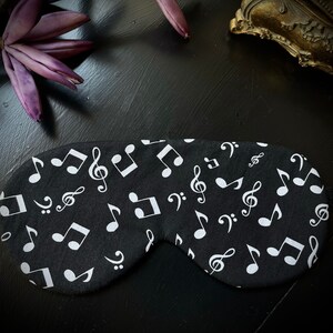 Könnte beinhalten: Schwarze Schlafmaske mit einem weißen Notenmuster.