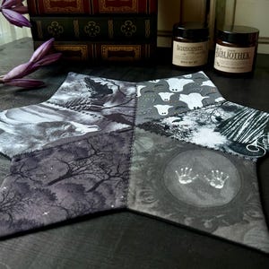 Könnte beinhalten: Ein sechszackiger sternförmiger Stoffuntersetzer mit Patchwork-Design. Jede Spitze des Sterns zeigt ein anderes Schwarzweißbild, darunter Bäume, Geister und Hände.