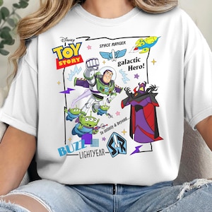 May include: A white t-shirt featuring a graphic print of Buzz Lightyear, Zurg, and green aliens from Toy Story. The design includes the text Disney Toy Story, Space Ranger, galactic Hero!, To Infinity & beyond..., and Buzz Lightyear with a logo.