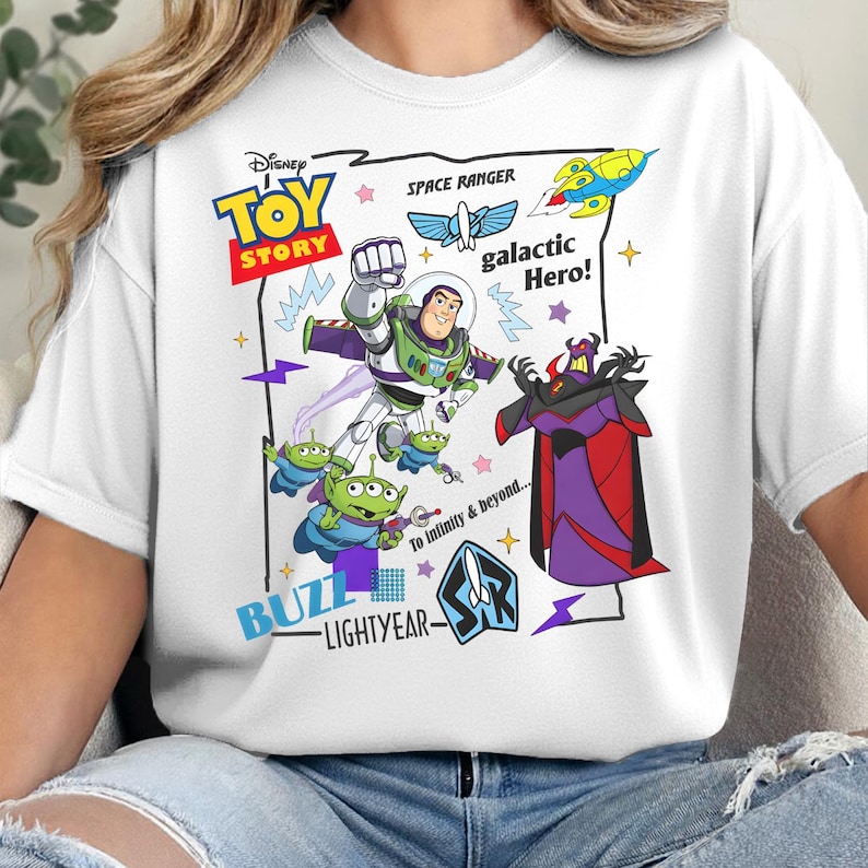 May include: A white t-shirt featuring a graphic print of Buzz Lightyear, Zurg, and green aliens from Toy Story. The design includes the text Disney Toy Story, Space Ranger, galactic Hero!, To Infinity & beyond..., and Buzz Lightyear with a logo.