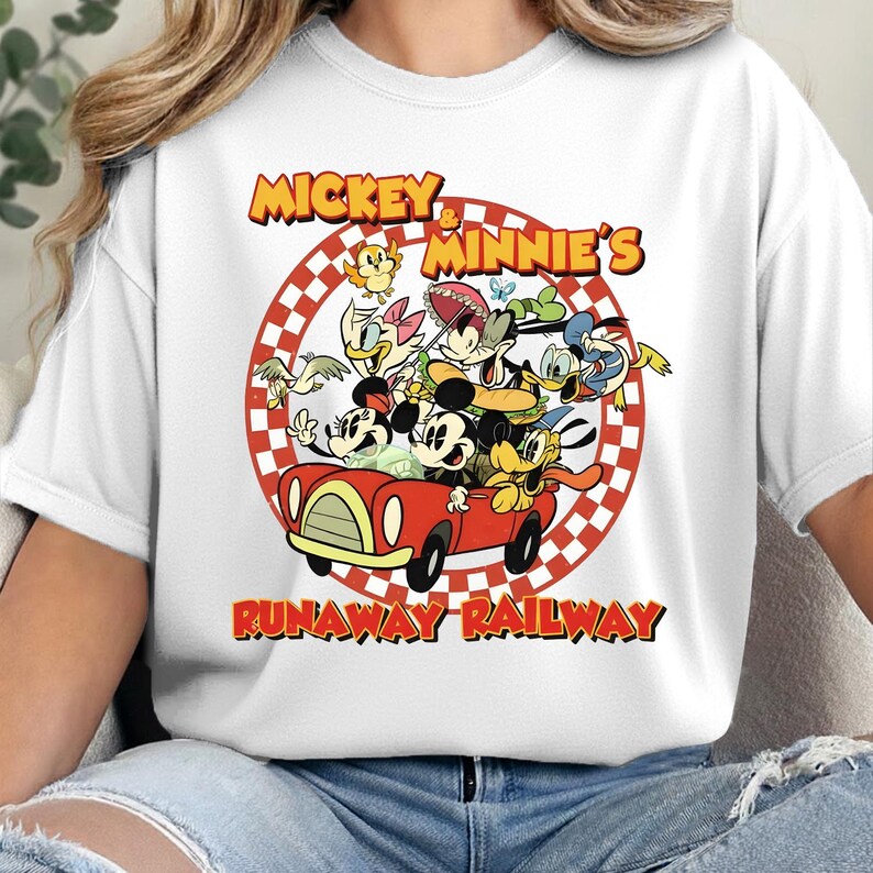 May include: White crew neck t-shirt featuring a graphic of Mickey and Minnie Mouse with other cartoon characters in a red car. The text "Mickey & Minnie's Runaway Railway" is displayed in yellow and red.