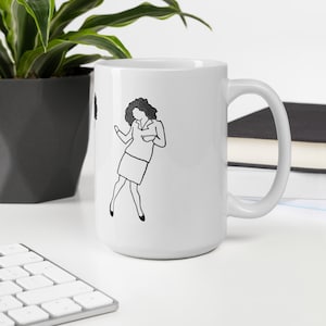 May include: White ceramic coffee mug featuring a black line drawing of a woman with curly hair wearing a skirt and blouse. The woman is dancing.