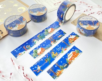 May include: Four rolls of blue washi tape with winter scenes. The tape features illustrations of snowmen, houses, deer, and trees. The text on the tape reads "Cozy Winter Washi Tape" and "Happy Winter 2024".