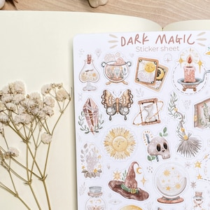May include: A sticker sheet with a variety of dark magic themed illustrations. The sheet includes a witch's hat, a crystal, a butterfly, a cauldron, a sun, a skull, a candle, an hourglass, a hand with stars, a potion bottle, and a magic ball.