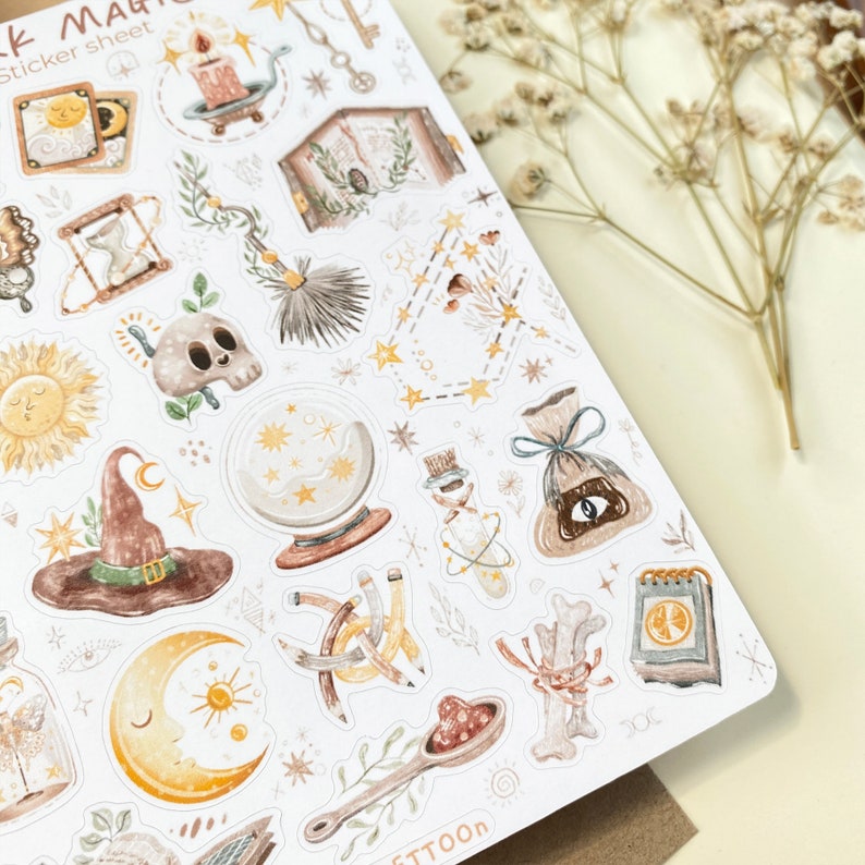 May include: A sheet of stickers featuring a variety of whimsical illustrations in a muted color palette. The stickers include a witch's hat, a crystal ball, a skull, a sun, a moon, a potion bottle, a bag of coins, a key, a candle, a book, a feather, a bone, a spoon, and stars. The stickers are perfect for adding a touch of magic to your planner, journal, or scrapbook.