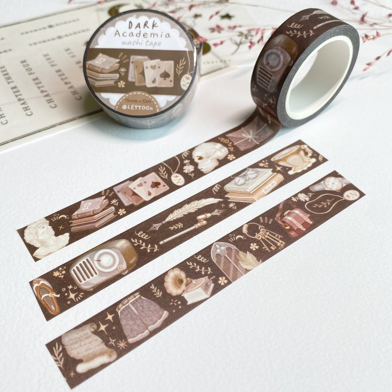 Peut inclure: Trois rouleaux de ruban adh&eacute;sif washi brun avec des illustrations de livres, de cl&eacute;s, d'un cr&acirc;ne, d'un gramophone, d'une plume et d'une horloge. Le ruban est &eacute;tiquet&eacute; "DARK Academia washi tape" et "15mm x 10m @LETTOON".
