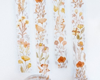 May include: Four rolls of washi tape with floral designs in shades of orange, yellow, and brown. The tape is on a white background. The text "MELLO FLA" is visible on the roll of tape.