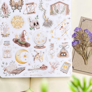 May include: A sheet of stickers featuring various illustrations in a whimsical style. The stickers include a witch's hat, a crystal ball, a moon, a sun, a butterfly, a book, a skull, a broom, a potion bottle, and more. The stickers are all in shades of brown, yellow, and white.