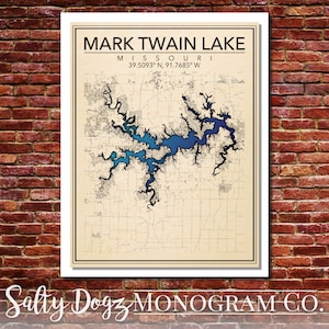 May include: A vintage-style map of Mark Twain Lake in Missouri, with the lake highlighted in shades of blue. The coordinates 39.5093° N, 91.7685° W are printed below the lake name. The map is framed with a white border and has a beige background.