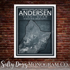 May include: A black and white map of Andersen Air Force Base in Yigo, Guam. The map is on a blue background with a white border. The text "UNITED STATES AIR FORCE BASE ANDERSEN YIGO, GUAM 13° 34' 31.19" N: 144° 55' 16.79" E" is printed below the map. The text "Salty Dogz MONOGRAM CO." is printed below the map.