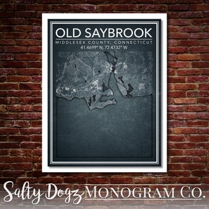 May include: A framed map print of Old Saybrook, Connecticut, with the text "OLD SAYBROOK" at the top. The map shows the town's layout in grayscale, with coordinates 41.4699° N, 72.4732° W. The bottom text reads "Salty Dogz MONOGRAM CO."