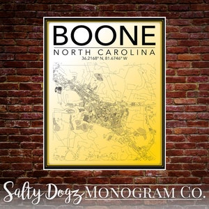 May include: A black and white map of Boone, North Carolina, with the text "BOONE NORTH CAROLINA 36.2168° N, 81.6746° W" printed above the map. The map is on a yellow background and is framed in black. The text "Salty Dogz MONOGRAM CO." is printed below the map.