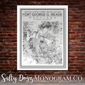 May include: A black and white map print of Fort George G. Meade, a United States Army installation in Maryland. The map shows the layout of the base, including roads, buildings, and other features. The text "UNITED STATES ARMY INSTALLATION FORT GEORGE G. MEADE MARYLAND 39.1043° N, 76.7342° W" is printed at the top of the map.