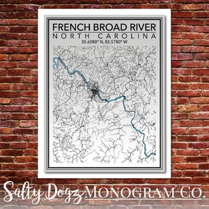 May include: A black and white map of the French Broad River in North Carolina. The river is highlighted in blue. The coordinates 35.6088° N, 82.5780° W are printed below the title. The text "Salty Dogz MONOGRAM CO." is printed at the bottom of the map.