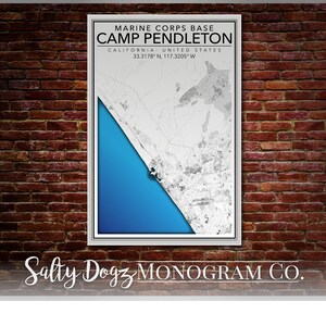 Peut inclure: Une carte en noir et blanc du Camp Pendleton, une base du Corps des Marines en Californie, avec un fond d'océan bleu. La carte est encadrée dans un cadre blanc et le texte "MARINE CORPS BASE CAMP PENDLETON CALIFORNIA UNITED STATES 33.3178° N, 117.3205° W" est imprimé au-dessus de la carte. Le texte "Salty Dogz MONOGRAM CO." est imprimé sous la carte.