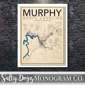 May include: A vintage-style map print of Murphy, North Carolina, with the city name and coordinates in black text on a cream background. The map shows the city's streets and waterways in black and blue lines.