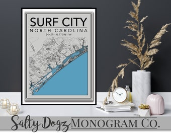 Può includere: Una mappa in bianco e nero di Surf City, Carolina del Nord, con il nome della città e le coordinate stampate in nero su uno sfondo grigio. La mappa mostra la costa e l'area circostante. Il testo "Salty Dogz MONOGRAM CO." è stampato in nero nella parte inferiore dell'immagine.
