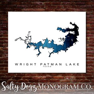 May include: A white canvas print featuring a detailed map of Wright Patman Lake in Texas. The lake is depicted in shades of blue, with the text "WRIGHT PATMAN LAKE TEXAS" below the map. The print is set against a brick wall.