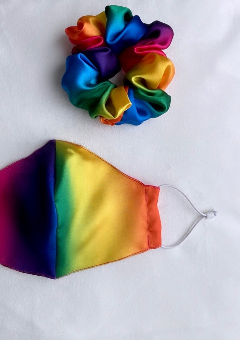 May include: A rainbow-colored satin scrunchie and a rainbow-colored face mask with a white elastic band.
