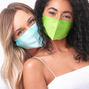 Puede incluir: Dos personas usando mascarillas. La persona de la izquierda lleva una mascarilla azul claro y la persona de la derecha lleva una mascarilla verde brillante.