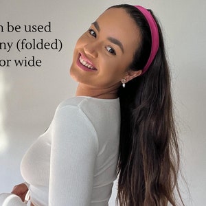 Könnte beinhalten: Eine Frau mit langen braunen Haaren trägt ein weißes Langarmshirt und ein rosafarbenes Stirnband. Der Text "can be used skinny (folded) or wide" ist im Bild zu sehen.