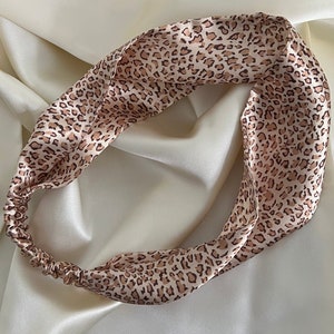 Può includere: Un cerchietto in raso con stampa leopardata marrone e beige.