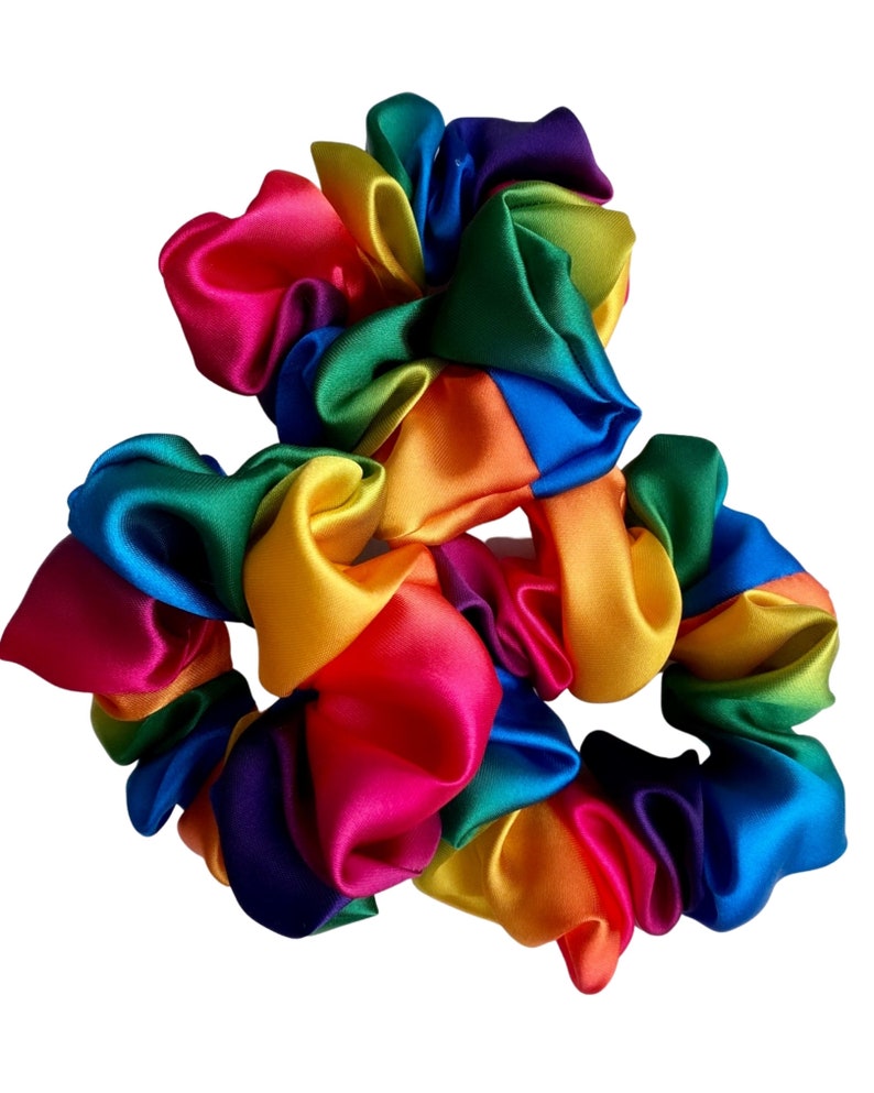 May include: Three rainbow-colored satin scrunchies. The scrunchies are made of a soft, silky fabric and are perfect for adding a pop of color to any outfit.