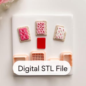 Può includere: Una superficie bianca mostra oggetti in miniatura a tema cibo e colorati. Tre pasticcini rettangolari con glassa e zuccherini rosa e bianchi sono disposti con un quadrato rosso. Il testo "Digital STL File" è visualizzato su uno striscione bianco.