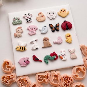 Può includere: Una collezione di abbellimenti colorati a forma di animali, tra cui una rana, una mucca, un pulcino, una pecora, un maiale, un cavallo, un cane, un uccello, una farfalla, una coccinella, un'ape, un agnello, un coniglio e un verme. Sono inclusi anche diversi tagliapasta a forma di animali.