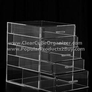 May include: A clear acrylic organizer with six drawers. The organizer is made of clear acrylic and has a modern design. The drawers are all the same size and are perfect for storing small items.